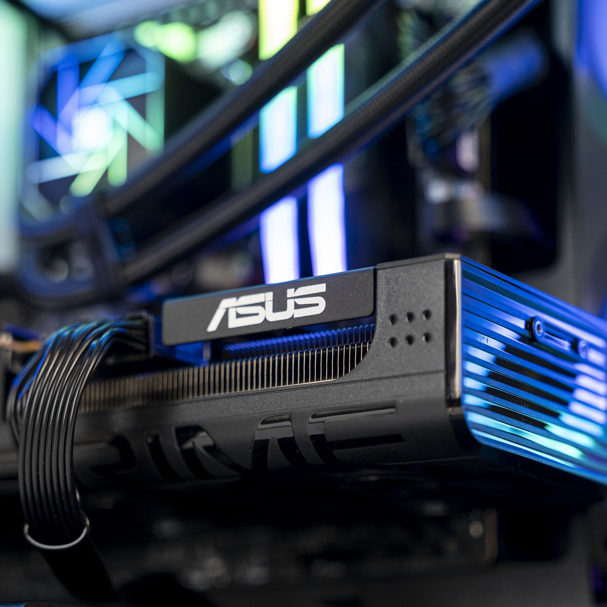 ASUS graphics card with a black heatsink and vibrant blue LED lighting reflection, shown inside a computer case with other PC components in the background.